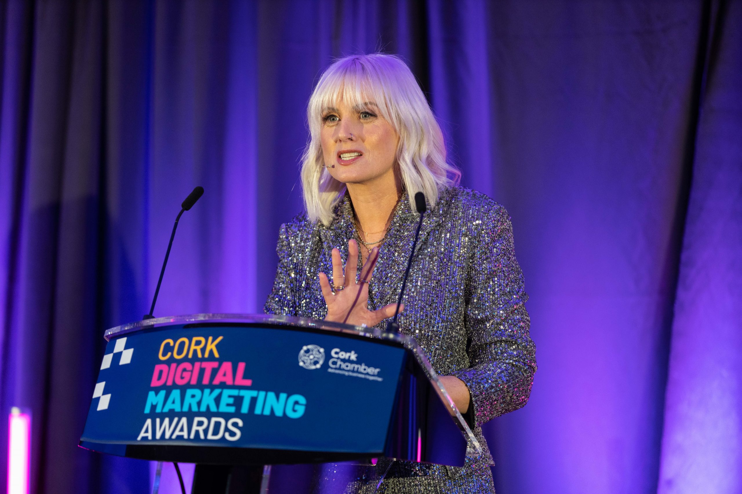 sinead kennedy, RTE presenter, host of the Cork Digital Marketing Awards stands onstage nehind the CDMA podium