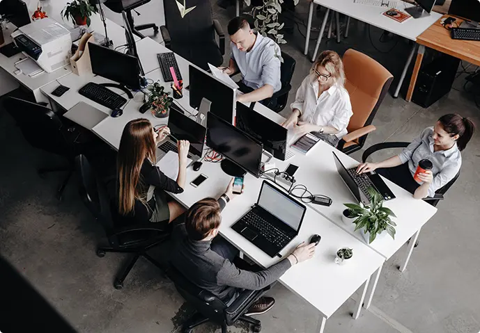 Office workers sat at bench desking workstations, working on computers