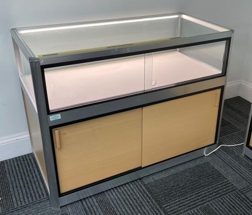Used Storage Unit, With Sliding Doors & LED Lights In Top Display Section - 1200mm Width x 600mm Depth x 900mm High. 2 In Stock