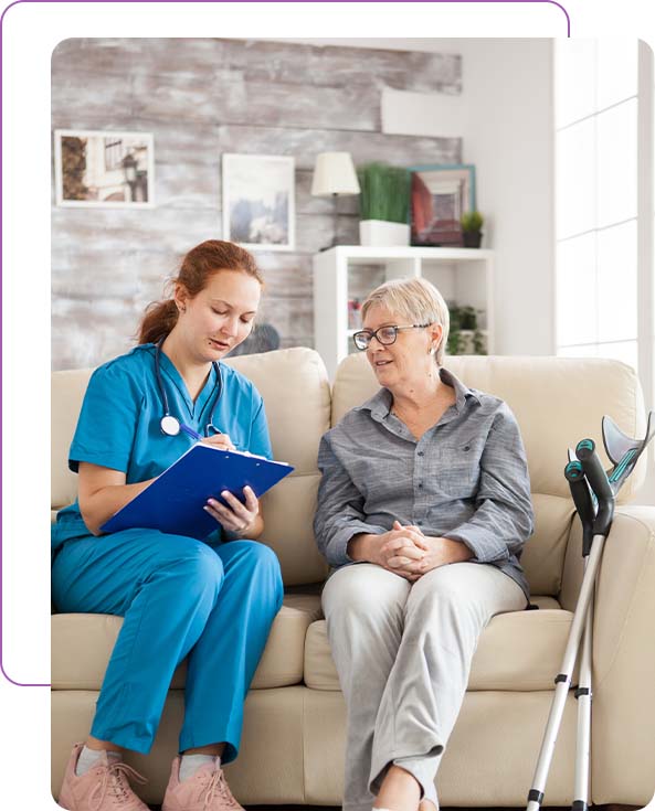 female doctor with a senior woman sitting on a sofa in a nursing home writing a prescription on a clipboard